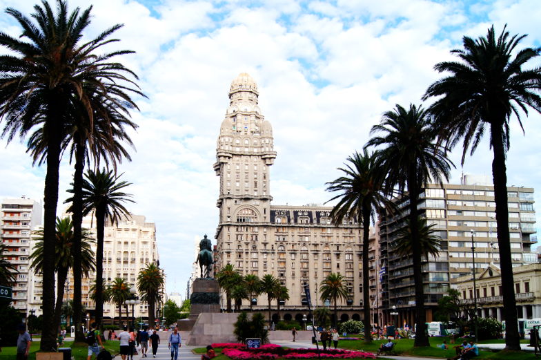 Der Plaza Independencia in Montevideo ist von imposanten Gebaeuden, Palmen und Statue umgeben