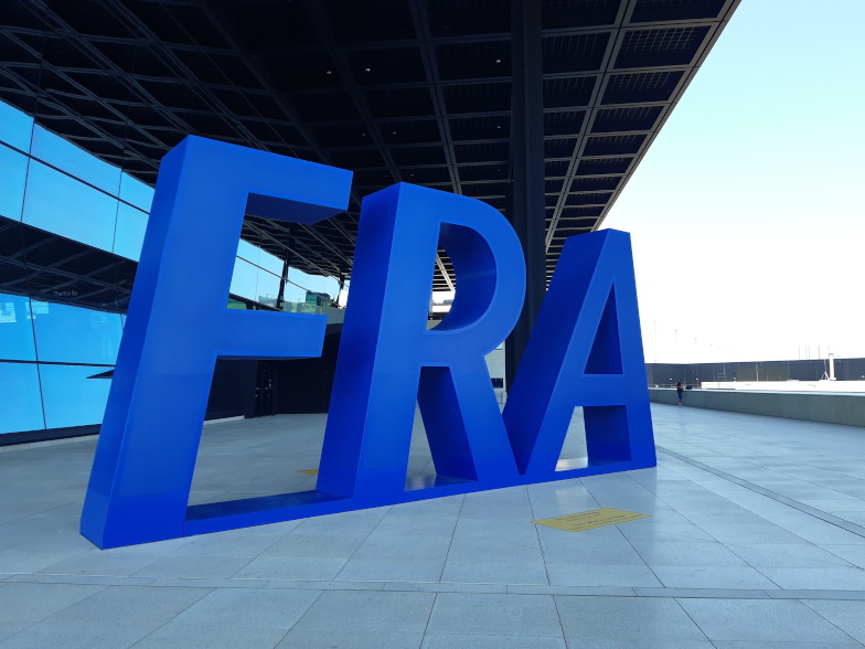 Großer blauer FRA-Schriftzug vor dem Flughafen Frankfurt
