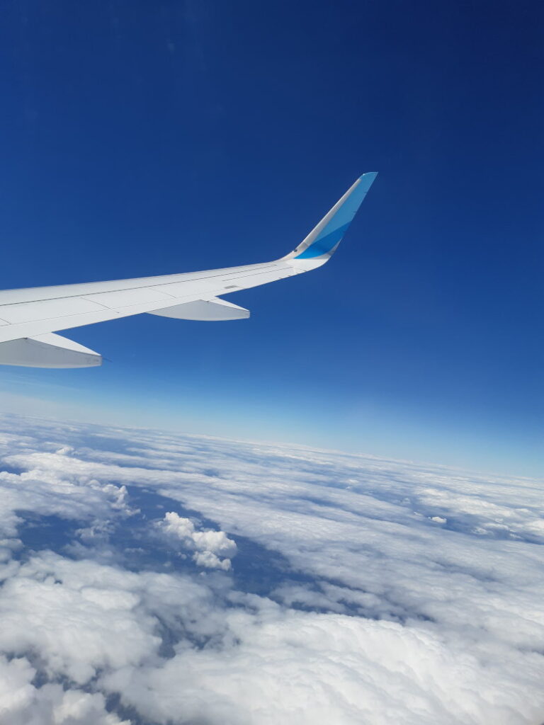Blick aus dem Flugzeugfenster auf die Tragfläche über den Wolken