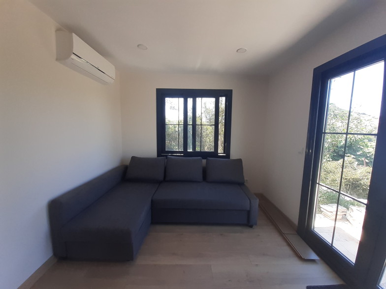 Gemütliche Sofaecke im Tiny House mit Blick durch das Fenster ins Grüne