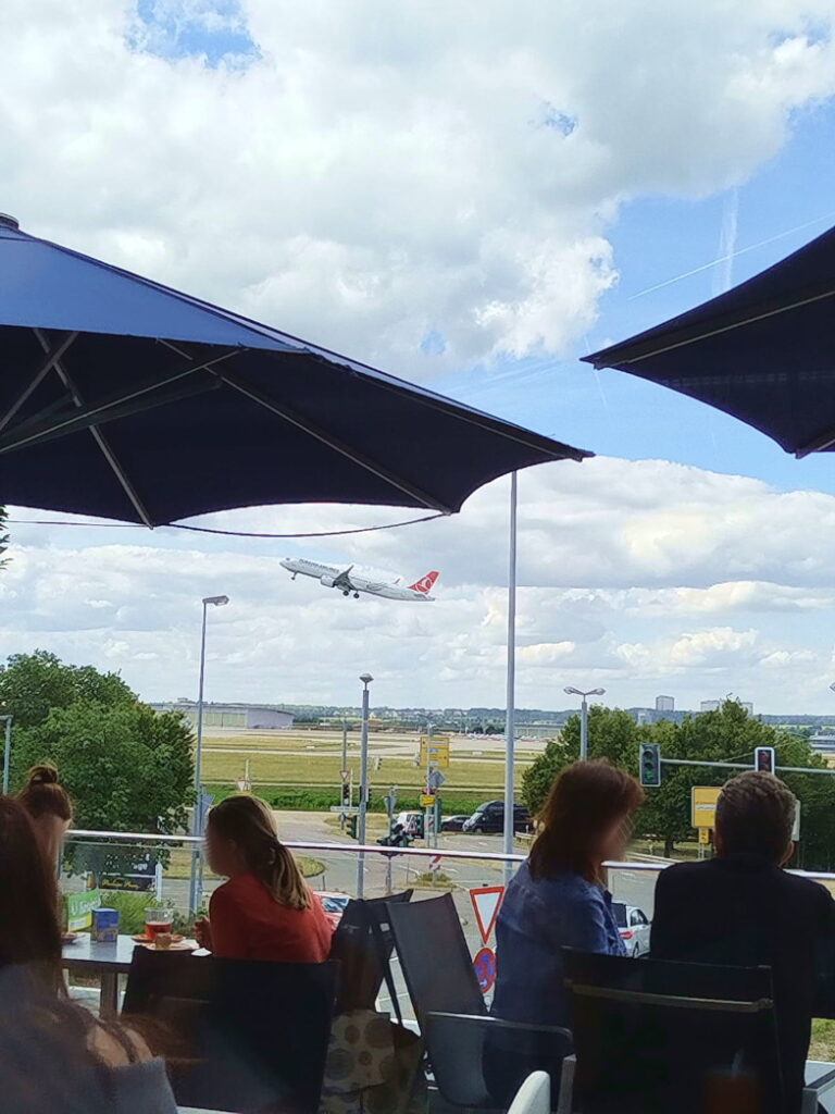 Startendes Flugzeug am Flughafen Stuttgart, beobachtet von der Terrasse der Bäckerei Schill