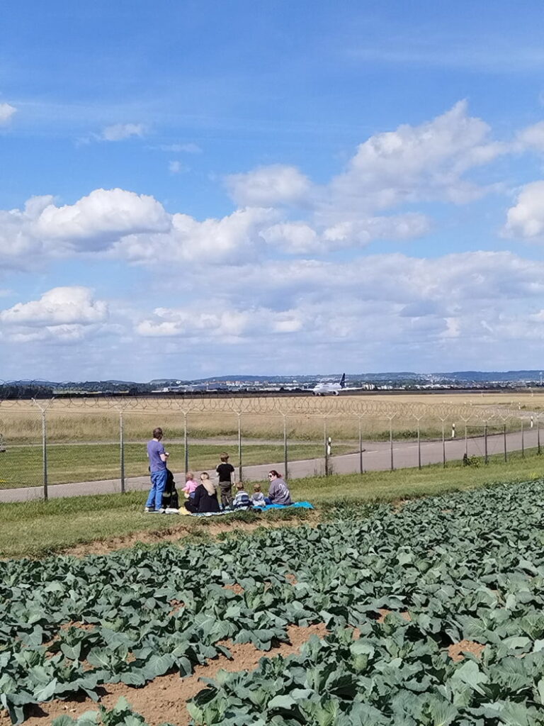 Picknick auf der Wiese am Flughafenzaun in Stuttgart beim Flugzeuge beobachten