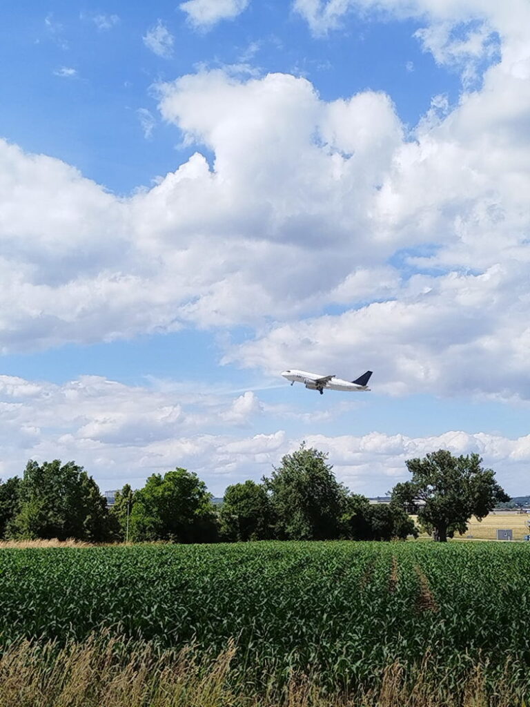 Tiefflug eines Flugzeugs über dem Feld am Flughafenzaun in Stuttgart
