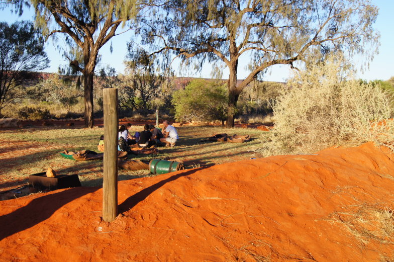 Campingplatz im australischen Outback mit rotem Sand und Bäumen in der Nähe des Uluru